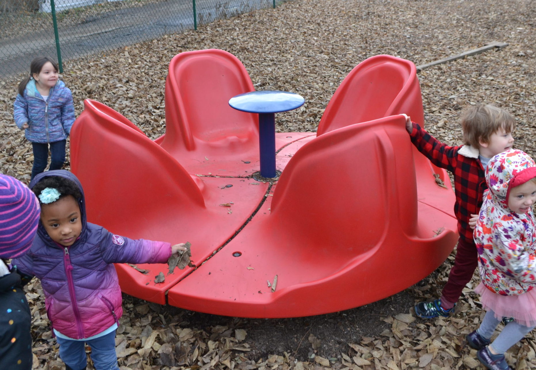 Inclusive Playgrounds Children playing on a physically-inclusive merry-go-round perfect for children with disabilities