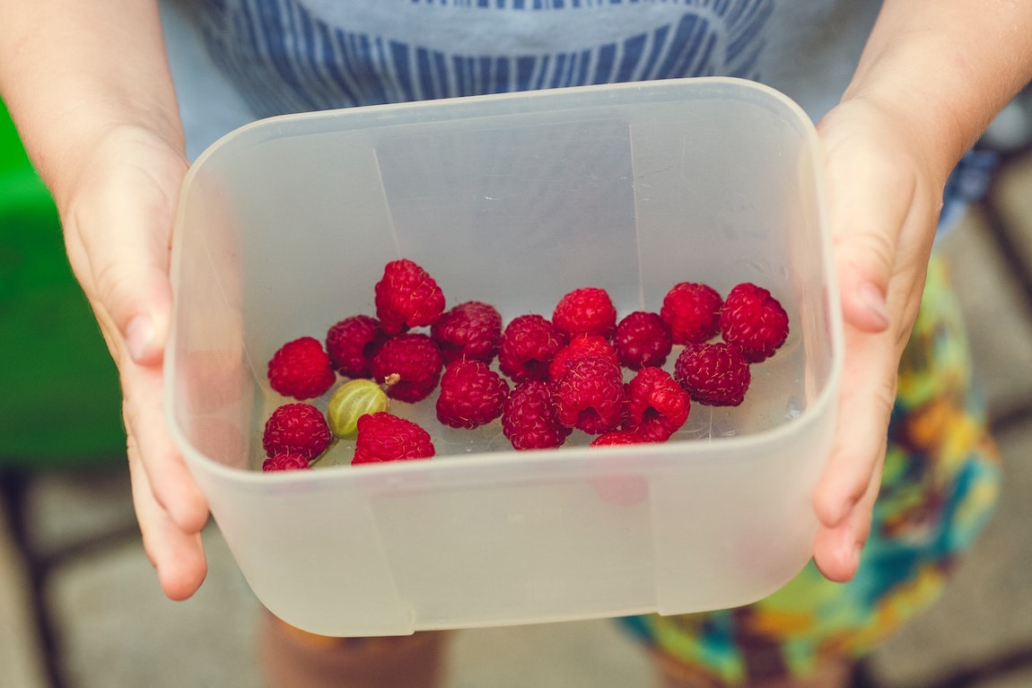 Child holding raspberries in a bowl